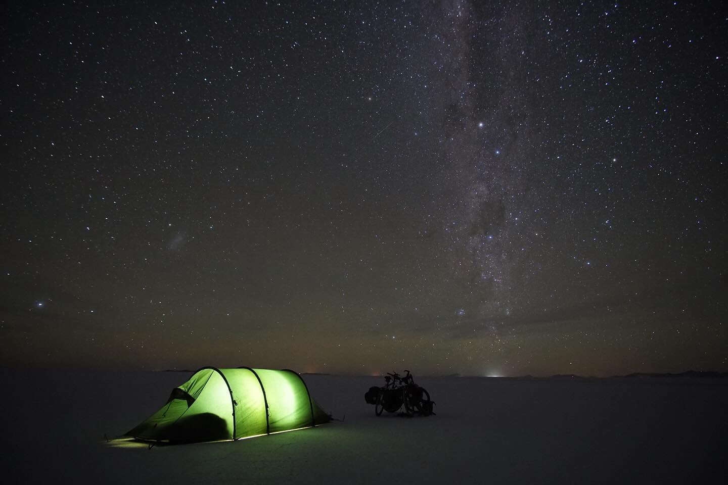 Die drei Tage ohne Fahrrad taten gut, doch wir freuten uns auch wieder weiter fahren zu können. Vorallem stand eines der absouluten Highlights an. Mit den Rädern auf den Salzsee. 1 ½ Tage nichts außer weiß. Keine Straßen, keine Menschenseele, nur wir mit unseren Fahrrädern. Man fährt km um km und man verliert jegliche Orientierung. Der Süden sieht genauso aus wie der Norden oder der Westen oder der Osten. Nur eine kleine Orientierung am Horizont und die Sonne. Der Vulkan Tunupa der aber am Fuß auch über 15 km Breite hat. Ohne Navi hätten wir den Ausgang also auch so nicht gefunden. Ein nichts aus weiß und trotzdem unbeschreiblich schön. Doch das Fahren an sich war mühsam. Da die Regenzeit gerade erst zu Ende gegangen ist, war das Salz noch sehr nass und es fühlte sich so an, als würde man über Kleber fahren. Dazu hatte man das Gefühl gar nicht vom Fleck kommt. Am Nachmittag hielten wir deshalb einfach an und schlugen mitten auf der weißen Ebene unser Zelt auf. Genossen noch den wunderschönene Sonnenuntergang und gingen relativ früh schlafen. Denn wir wollten uns unbedingt den Sternenhimmel anschauen. Die Erwartungen waren zwar schon hoch, doch was wir sahen übertraf alles, was man sich hätte vorstellen können. Ein Bild, das keine Kamera einfangen kann. Ein Bild das einfach nur unbeschreiblich ist.
Die restlichen 60 km legten wir dann am nächsten Vormittag auf dem Salar zurück. Zum Glück auch mit besseren Bodengegebenheiten, sodass wir nicht mehr nur noch das Gefühl hatten, am Boden zu kleben.
Doch der Salzsee hat auch Spuren hinterlassen. Nicht nur wir waren von oben bis unten voller Salz, auch unsere Taschen und Fahrräder waren komplett gesalzen. Das konnte natürlich unmöglich so bleiben, da dir Fahrräder sonst wahrscheinlich schon auf dem Weg nach La Paz völlig verrostet gewesen wären. Wir verbrachten also den ganzen Nachmittag damit, unsere Fahrräder in der Wasserquelle vom Vulkan (die einzige Wasserquelle, die nicht salzig war) sauber zu machen.
